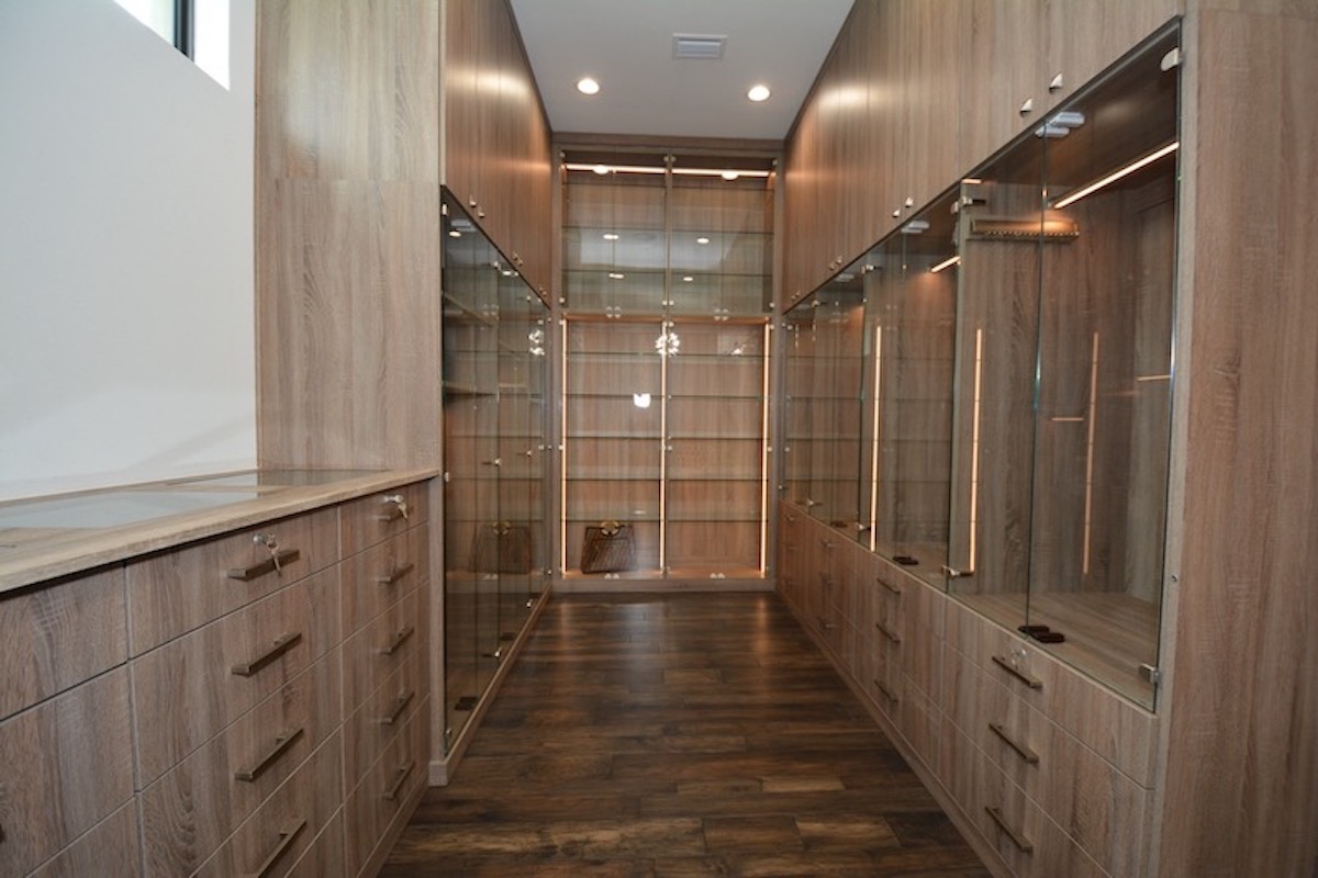 A spacious walk-in closet with custom lighting and glass doors.