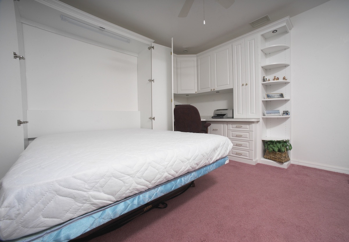 A home office featuring custom cabinets and a Murphy bed.