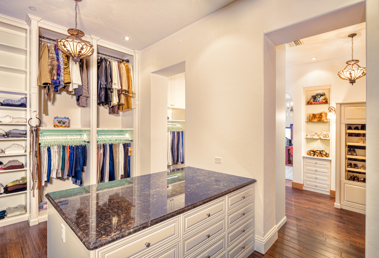 A spacious walk-in closet with island and custom cabinetry.